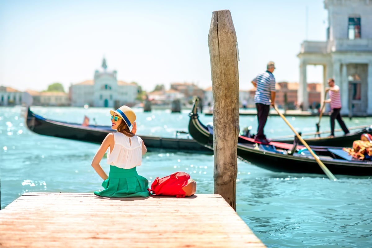 Female traveler sitting on a pier in Venice